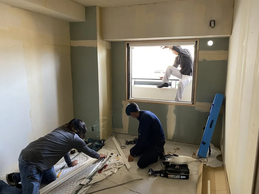 マンションの一室で新しい窓枠を取り付ける職人