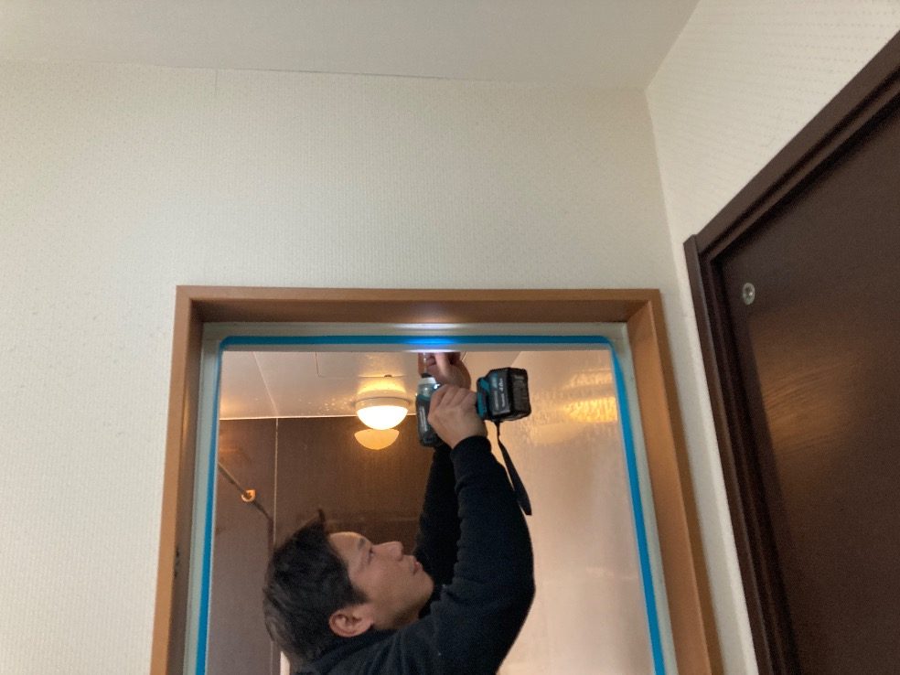 浴室の入口で新しいドアの枠を取り付けているスタッフ