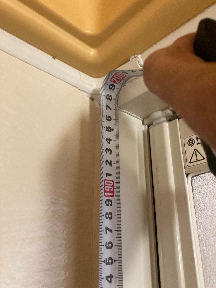 現地調査で浴室のドアの枠の高さを測っているところ